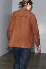 Blazer marrón de ante con cuello de solapa de muescas, manga larga, bolsillos de parche delanteros y cierre frontal con botones.