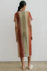 Vestido midi de red con estampa degradé en tonos naranja, beige y verde. Tiene tajos a los costados.