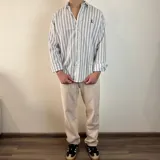 Camisa celeste y blanca a rayas verticales, de manga larga con puños abotonados y cuello clásico.