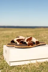 Sandalias bajas de cuero con estampado animal print de vaca en marrón y blanco.