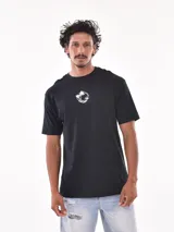 Remera negra de corte oversized con estampado circular en el pecho que incluye una palmera, una ola y la palabra 'Paradise'.