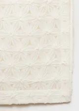 Falda midi color crudo con diseño calado de flores en relieve, tiro medio, corte recto, abertura lateral y cierre de cremallera lateral. Incluye forro interior.