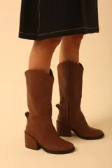Botas de cuero color marrón con caña media, taco cuadrado y cierre lateral. Diseño de estilo western con puntera fina y detalle de costuras en la caña.