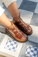 Sandalias de cuero color marrón con textura de cocodrilo, plataforma con suela track y tiras finas que se atan al tobillo.