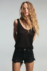 Short de jean de tiro alto, color celeste claro desgastado, con roturas grandes y deshilachado en el bajo. Presenta cinco bolsillos y cierre frontal con botón metálico.