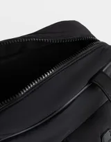Cartera bowling negra de tela deportiva con manijas superiores y cierre superior. Tiene doble bolsillo frontal con hebilla, bolsillos laterales con broche y charm lateral.