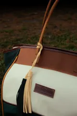 Bolso de fin de semana tipo tote bag, con paneles de lona color borgoña y azul marino, detalles en gamuza marrón y manijas de cuero. Incluye bolsillo interior y cierre superior.