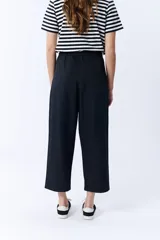 Pantalón negro de corte ancho, con pinzas en la cintura y bolsillos laterales.