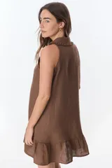 Vestido corto color ladrillo, sin mangas, con cuello camisero con volados, abotonado al frente y falda con volados.