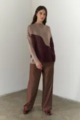 Buzo de punto con diseño geométrico en bloques de color gris y negro, de cuello redondo y mangas largas.