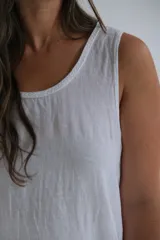 Vestido largo blanco de lino italiano sin mangas, con escote redondo y detalle trenzado. Cuenta con bolsillos en los costados.