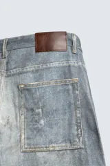 Pantalón de jean azul con efecto lavado y estampado, corte holgado y amplio en toda la pierna, tiro medio, cinco bolsillos y cierre frontal con cremallera y botón.