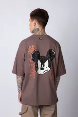 Remera blanca de algodón de corte oversize con mangas cortas y cuello redondo. Presenta un pequeño estampado en el frente con la figura de Mickey Mouse y caracteres orientales.