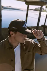 Gorra marrón de cinco paneles con bordado frontal con la inscripción "TT Archive Club Creative Dept. Established 1990".