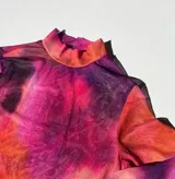 Top de malla traslúcida con cuello alto y mangas largas, con estampado abstracto en tonos fucsia, naranja y violeta.