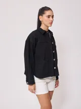 Campera marrón de algodón con cuello camisero, cierre con botones a presión, bolsillos frontales y corte holgado.