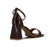 Sandalia de tacón alto color blanco, con una tira delgada sobre los dedos y pulsera con hebilla al tobillo.