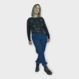 Buzo negro de punto con cuello redondo y manga larga. Presenta un estampado floral en tonos dorados y azules en el frente.