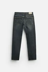 Pantalón de jean azul oscuro, corte slim fit, tiro medio, cinco bolsillos, tejido elástico y efecto lavado.