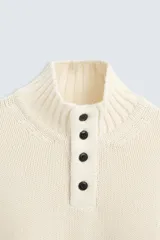 Jersey color crudo de corte recto, tejido en hilatura con mezcla de algodón y lana. Cuello subido con cierre frontal de botonadura y manga larga.