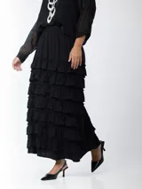 Falda larga negra con cintura elástica y múltiples volados horizontales.