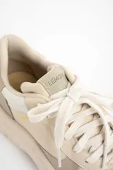 Zapatilla urbana de mujer con plataforma gruesa, combinando paneles de cuero liso y gamuza en tonos beige y nude. Presenta cordones blancos y la palabra "LEMON" estampada en dorado en el lateral.