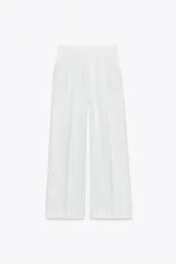 Pantalón blanco de tiro alto con pinzas delanteras, bolsillos laterales y cintura elástica en la parte trasera.