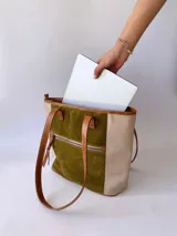 Bolso tipo tote de cuero color verde oliva con laterales de cuero texturizado color beige y manijas de cuero color marrón.