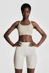 Top deportivo color beige de tejido acanalado con tecnología DryMove™ que absorbe el sudor. Tiene breteles finos, espalda nadadora, copas forradas con relleno extraíble y bajo elástico acanalado.