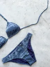 Conjunto de bikini negro con textura, compuesto por un corpiño de triángulos movibles con tirantes finos y una bombacha vedetina ancha con laterales fijos.