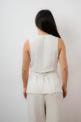 Chaleco sastrero color crudo, con escote en V y cierre frontal con botones.