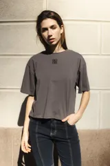 Remera negra de algodón con corte cuadrado, cuello redondo y logo bordado en color naranja.