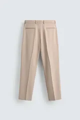 Pantalón de vestir color beige, corte slim fit, confeccionado en tejido con viscosa. Cuenta con bolsillos frontales y traseros de doble vivo con botón. Cierre frontal con cremallera y botón.