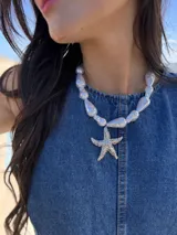 Collar corto con cuentas simil perla irregulares y dije de estrella de mar en acero quirúrgico. Se cierra con cadena y ganchito para regular el largo.