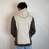 Canguro con capucha color marrón y beige, con logo bordado en el pecho y bolsillo tipo canguro.