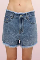 Short de jean azul con calce ajustado, tiro alto y ruedo desflecado. Presenta una lluvia de pequeñas piedras termo adhesivas que generan un brillo delicado.