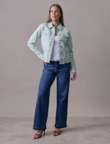 Campera de jean blanca, marca Baccini, con cuello solapa, bolsillos delanteros, abertura central con botones metálicos y terminación desflecada en el ruedo.