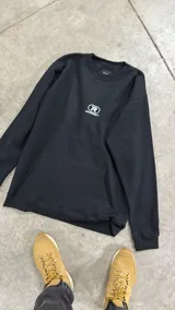 Buzo negro de frisa amplio sin capucha con bolsillo frontal, estampa delantera con logo RFN Project, etiqueta bordada en alta definición cocida en puño derecho y ajustes con tancas en la cintura.