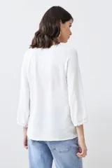 Blusa color crudo con escote en V y mangas largas.