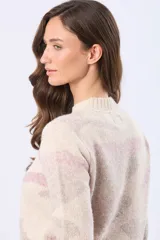 Buzo tejido de cuello redondo, color beige con estampado abstracto en tonos rosados y grises. Tiene mangas largas con puños acanalados y un pequeño parche de cuero sintético en el dobladillo.
