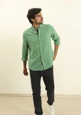 Camisa azul marino de lino y algodón, con cuello abotonado, manga larga con puños enrollados, bolsillo de parche en el pecho y cierre frontal con botones.