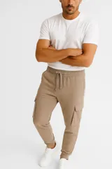 Pantalón jogging color beige con bolsillos cargo laterales, corte ajustado en los tobillos y cintura elástica con cordón ajustable.