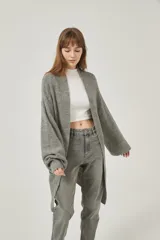 Saco largo de tejido de punto grueso color gris, con mangas largas y bolsillos frontales. Diseño holgado y sin cierre.