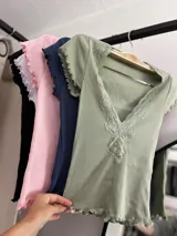 Remera corta color verde agua, con escote en V y detalle de puntilla blanca en el borde.