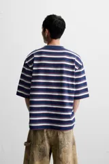 Camiseta de hombre a rayas horizontales azul marino, blancas y rojas, de corte relaxed fit, cuello redondo y manga corta.