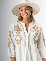 Vestido corto blanco de algodón italiano con bordado azul, mangas tres cuartos y botones frontales.