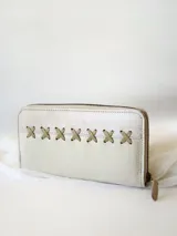 Billetera de cuero color crudo con cierre metálico y diseño de cruces caladas. Incluye monedero interno y espacio para billetes extendidos.