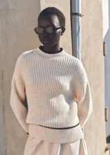 Sweater color crema de punto acanalado, con cuello alto y ribetes negros en cuello y ruedo.