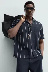 Camisa de hombre a rayas verticales color beige y blanco, de corte relaxed fit, manga corta y cuello bowling.