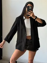 Blazer negro de lino con corte clásico, solapas de muesca y bolsillos delanteros con solapa.